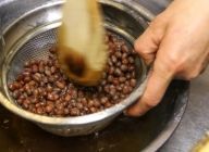 豆をザルにあけ、水を張ったボウルの中で裏ごしをする。