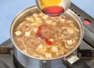 スープのとろみを確認し、溶き卵を流し入れ、酢を加え、スープを軽く沸騰させ、ラー油を加える。器にスープを盛り付ける。