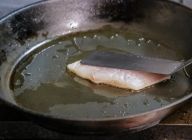 フライパンにオリーブオイルを入れ、温める前から魚を皮目を下にして入れ、弱火で焼く。そのとき、魚が反るので、パレットなどでやさしく押さえる。