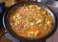 同じ鍋で玉葱とニンニクを色づくまで炒め，ブイヨン・トマトピューレ・サフラン・貝の煮汁を加え沸騰させる。そこに鶏・ソーセージを戻し、米と野菜を加え、沸騰させる。