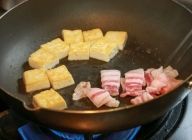 豆腐の両面に焼き色がついたら豚肉をフライパンに加える。
