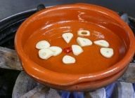 カスエラ（耐熱陶器）にオリーブオイルとニンニク、赤唐辛子を入れて中火にかける。
