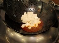 そのフライパンに豆腐をゆっくり入れる。そこへ鶏がらスープ・酒・醤油・胡椒を入れて味付けをし、葱を入れる。