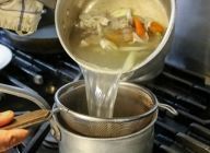 煮込んだスープを、ザルで濾す。