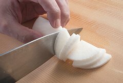 大根の丸みのあるほうを手前にしてまな板に置き、大根を片方の指で押さえ固定する。包丁の刃先で、端から均一の厚さに切る。