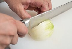 縦に均等な切り目を入れる。玉ねぎの根元が手前の時は包丁の刃元で、逆に向こう側の時は包丁の刃先を使う。切りやすい向きでOK。