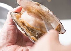貝殻にヘラを差し込み、貝を広げて開く。貝上部にヘラを入れ、小刻みにナイフを動かしながら繋がっている部分をはがす。