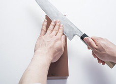 包丁の刃元の面が研ぎ石に当たるように包丁を持つ手を少し持ち上げ、包丁に少し角度をつけて、斜め上下に滑らせる。